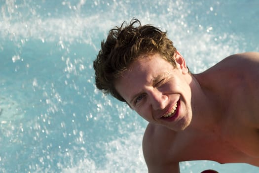 Happy man in the swimming pool with splashing water