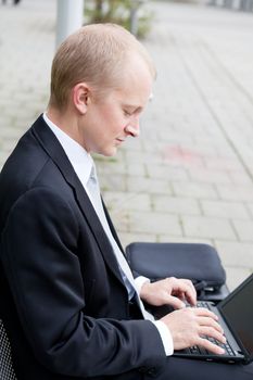 business man sitting outdoor working with notebook in summer