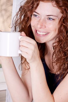 pretty young redhead woman with freckles and coffe smile and laugh