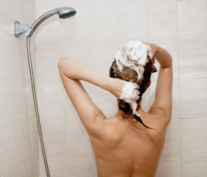 young brunette woman is taking shower and washing hair