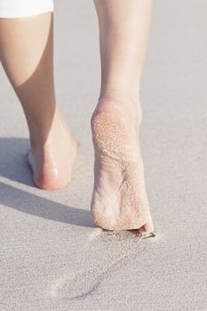 walking barefoot in the sand in summer holidays on beach