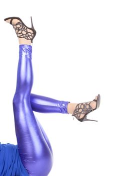 Cropped view image of a woman's sexy legs clad in shimmering blue leggins and stilettos
