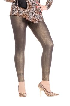 Cropped view image of a woman's sexy legs clad in shimmering golden leggins and stilettos