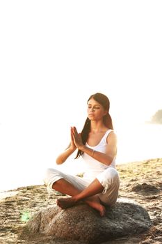 Young woman practicing yoga  near the ocean