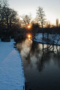 Beautiful winter sunset with trees and a small river in the snow vertical image