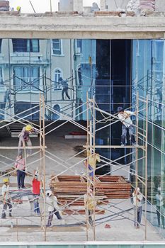 Scaffold workers erecting a scaffold on the upper floors of a high rise development on July 10, 2012 in Bombay, India. Local culture where workers operate in open toe slippers or bare feet.