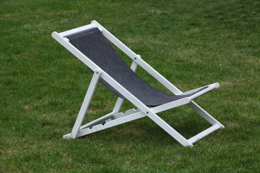 White wooden deck chair on green grass