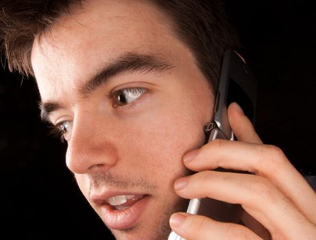 Young man talking on a cell phone, black backgound