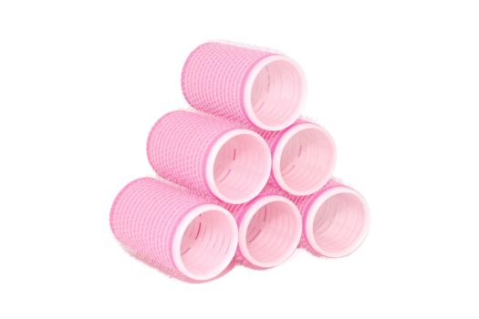 Six pink velcro rollers stacked in a pyramid, isolated on a white background