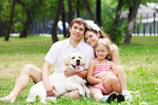 Young Family Outdoors in summer park with a dog