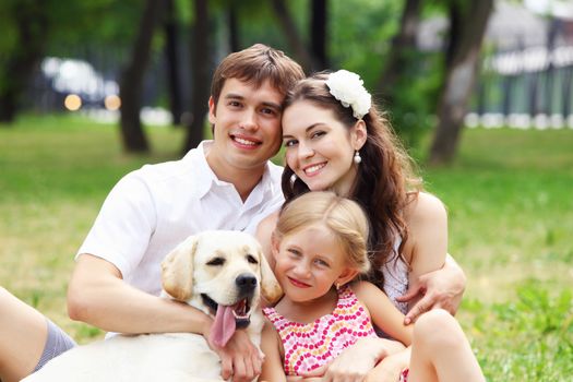 Young Family Outdoors in summer park with a dog