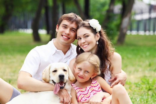 Young Family Outdoors in summer park with a dog