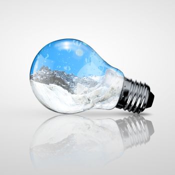 Electric light bulb and mountain inside it as symbol of green energy