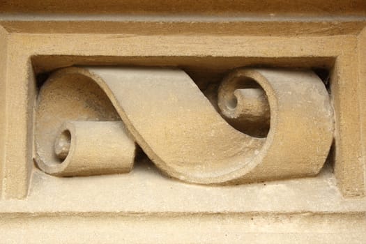 ribbon shaped detail carved in stone on facade of old house