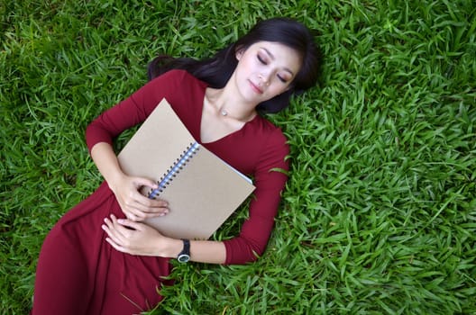 Woman lying on green grass with a book 