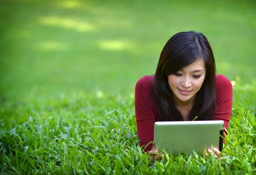 pretty woman using tablet outdoor laying on grass