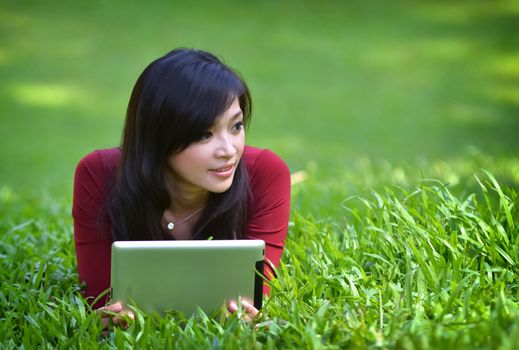 pretty woman using tablet outdoor laying on grass