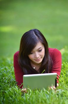 pretty woman using tablet outdoor laying on grass