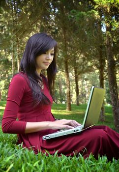 pretty  woman with laptop on green grass at the garden 