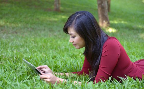 pretty woman using tablet outdoor laying on grass