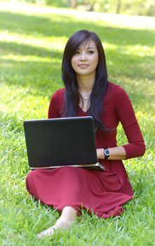 pretty  woman with laptop on green grass at the garden 