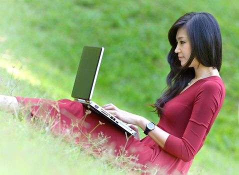 pretty  woman with laptop on green grass at the garden 