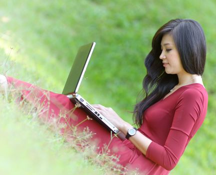 pretty  woman with laptop on green grass at the garden 