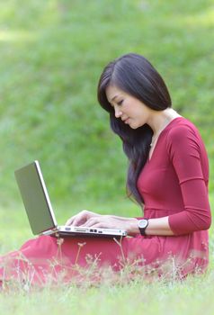 pretty  woman with laptop on green grass at the garden 