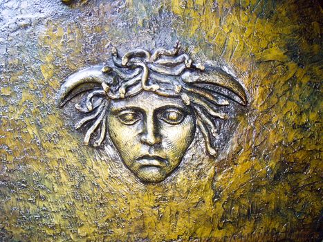 Fabled Medusa head with snakes on metal