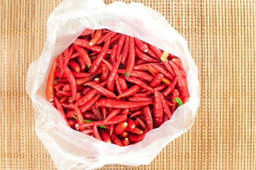 Red chilli in plastic bag on bamboo mat 