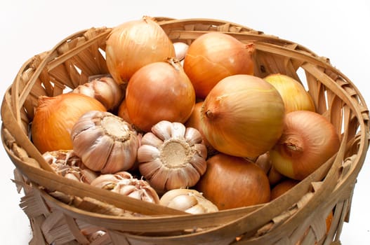 Garlic and onion bulbs in bamboo basket isolated on white background