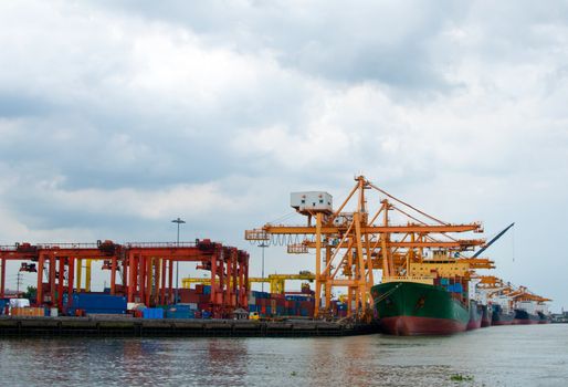 Industrial Container Cargo freight ship with working crane bridge in shipyard at dusk for Logistic background