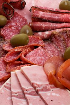 Background of Delicatessen Cold Cuts with Salami, Sausage, Baloney, Pepperoni and Green Olives closeup