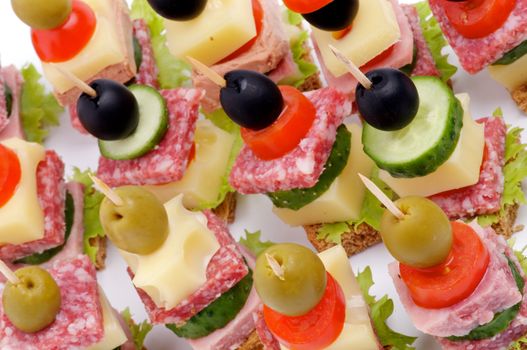 Background of Canape with Bacon, Salami, Tomatoes, Cheese, Cucumber, Green Olive, Black Olive, Lettuce and Whole Grain Bread closeup