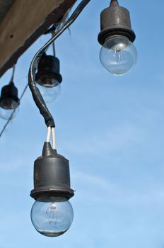 light bulb hanging from bare wires on blue sky background