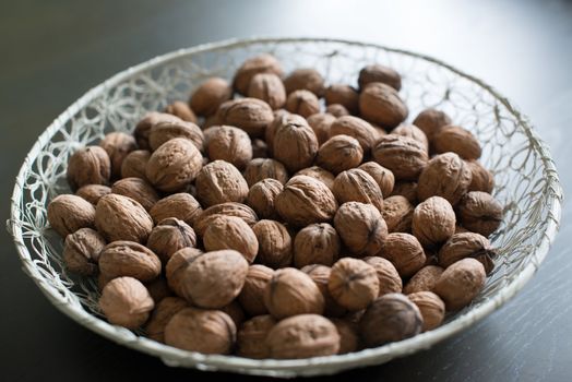 walnuts in a white basket on dark wooden table