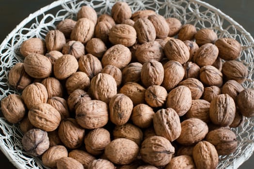 walnuts in a white basket on dark wooden table