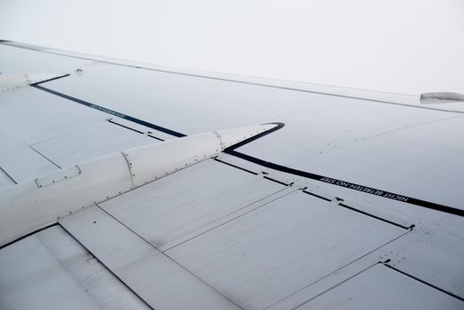 airplane wing, sky and clouds as seen through the cabin window