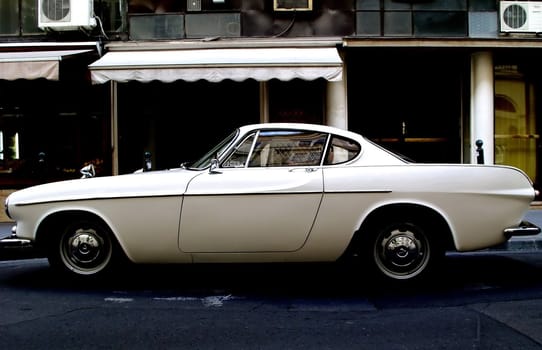 Old white car parking on the street. 