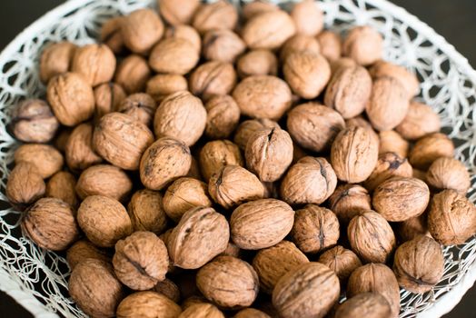 walnuts in a white basket on dark wooden table