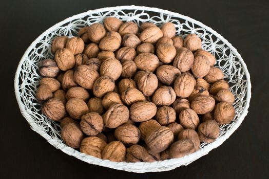 walnuts in a white basket on dark wooden table