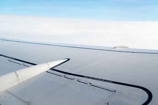 airplane wing, sky and clouds as seen through the cabin window