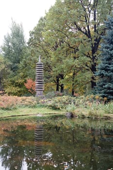 Autumn park with pond and decorative stone pagoda

