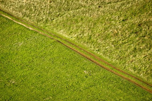 Green meadow diagonal tractor track aerial view