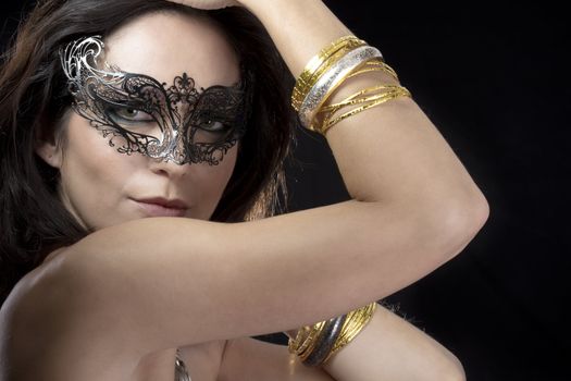 Sexy woman with venetian mask and gold and silver bracelets