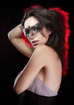 Sensual woman with bracelets of gold and silver, venetian mask with red light