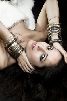 Woman lying and sensual with bracelets of gold and silver, green eyes