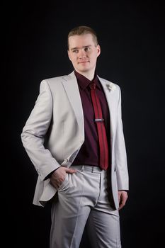 attractive young man in a gray suit and tie on a black background