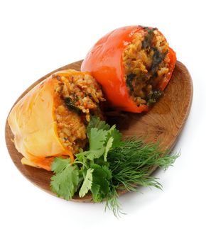 Stuffed Red and Yellow Bell Peppers Filled with Rice, Meat, Onion and Parsley close up on wooden plate