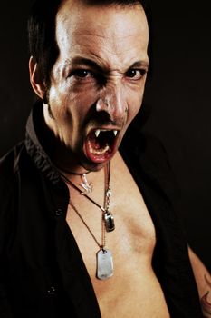 Photo of a male vampire with mouth open and fangs showing.  Harsh lighting and heavily filtered for scarier feel.